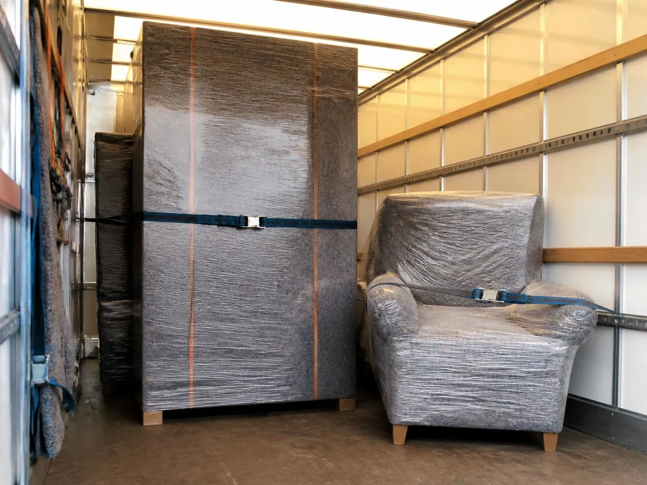 Wardrobe and armchair wrapped in blankets and strapped inside a VibeMove furniture removals van